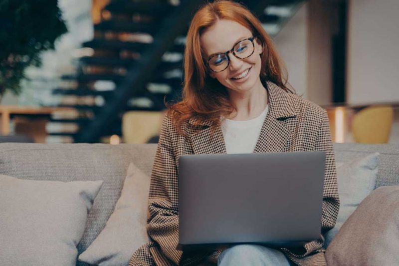 smiling woman in office attire with a laptop